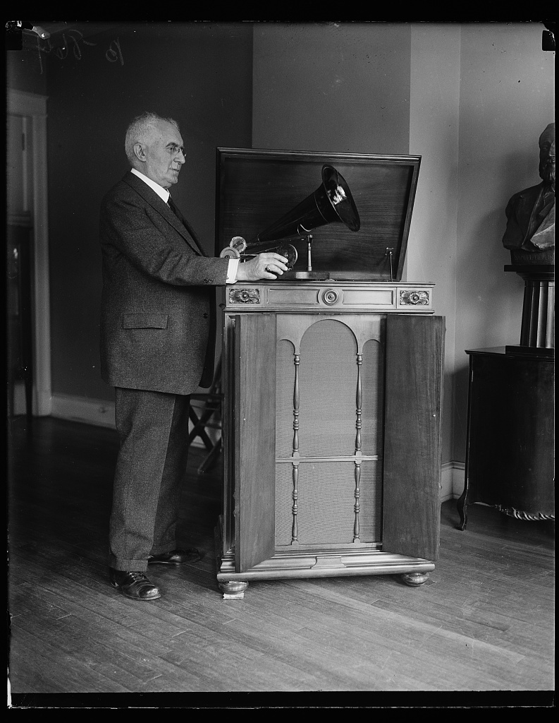 1927 年,贝利纳与早期唱机及 Victor Victrola Credenza 唱机合影。Harris & Ewing 摄,美国国会图书馆藏。